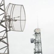 Four telecoms communication masts with transmitters and receivers for the mobile phone infrastructure on a misty cloudy grey day - Telekom Funkmasten Mobilfunk