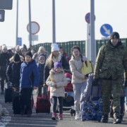 A Polish border guard assists refugees from Ukraine as they arrive to Poland at the Korczowa border crossing, Poland, Saturday, Feb. 26, 2022. (AP Photo/Czarek Sokolowski)