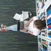 female student study in school library, using tablet and searching for information’s on internet. Listening music and lessons on white headphones