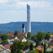 Mit 246 m (Metern) ueberragt der TK Elevator Testturm bei Weitem die Kirche des Ortes Zimmern ob Rottweil; der Aufzugstestturm fuer Express- und Hochgeschwindigkeitsaufzuege wurde von Thyssenkrupp Elevator zwischen 2014 und 2017 erbaut; Aufnahme von 13.08.2021;