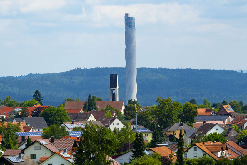 Mit 246 m (Metern) ueberragt der TK Elevator Testturm bei Weitem die Kirche des Ortes Zimmern ob Rottweil; der Aufzugstestturm fuer Express- und Hochgeschwindigkeitsaufzuege wurde von Thyssenkrupp Elevator zwischen 2014 und 2017 erbaut; Aufnahme von 13.08.2021;