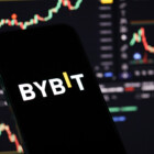 KYIV, UKRAINE - MARCH 15, 2024 Bybit logo on iPhone display screen and crypto currency value charts. Cryptocurrency exchange portal