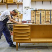 Kris Sullivan entfernt alten Lack von einer Anrichte "Modell 602k" der Deutsche Werkstätten Hellerau. Möbel aus den 50er bis 70er Jahren aus der DDR sind wieder sehr gefragt.