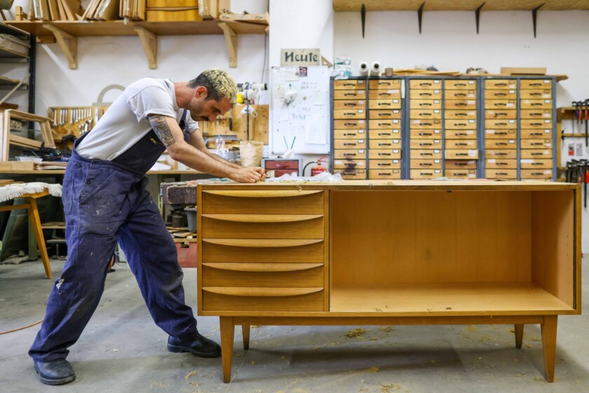 Kris Sullivan entfernt alten Lack von einer Anrichte "Modell 602k" der Deutsche Werkstätten Hellerau. Möbel aus den 50er bis 70er Jahren aus der DDR sind wieder sehr gefragt.